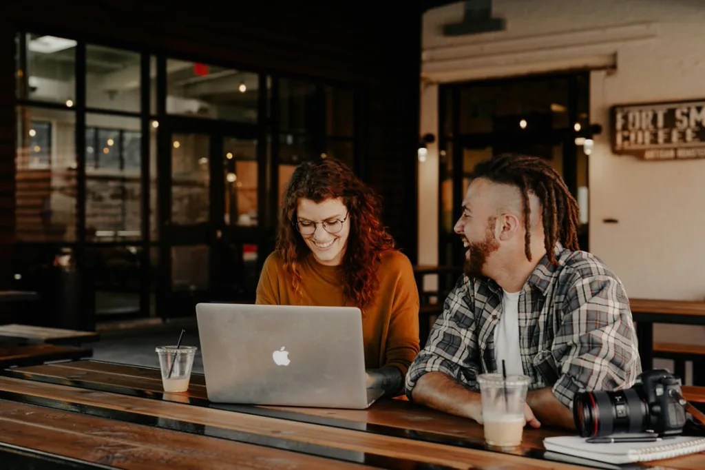Two people looking at a laptop together while sitting at a desk.
