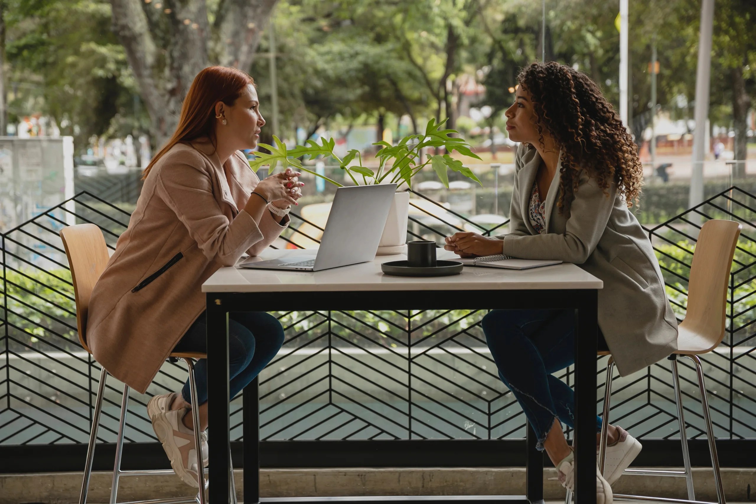 Two people sitting at a table discussing a project together.