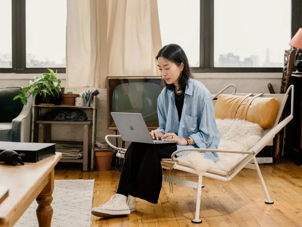 Woman sitting in a chair working on her laptop in an artfully decorated space.