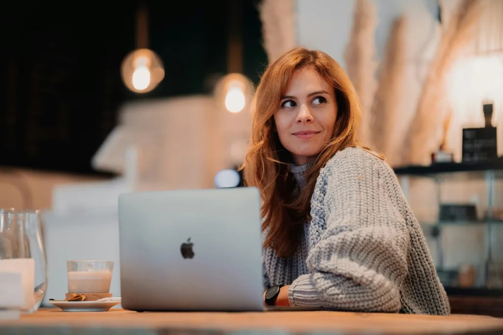 Woman sitting at a table with her laptop open in front of her.