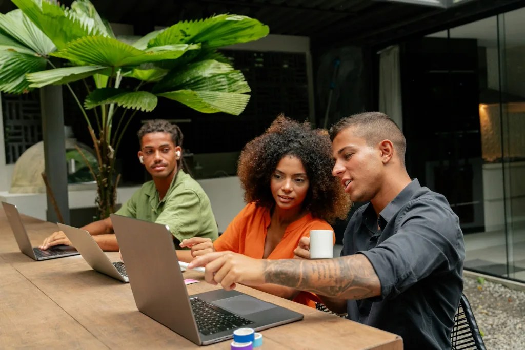 People sitting together at a shared table working on laptops.